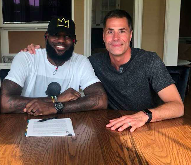 LeBron James shown with Rob Pelinka, signing with the LA Lakers.